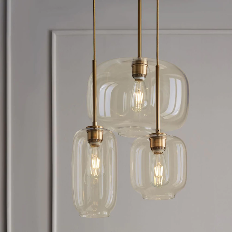 Brass and glass sculpted pendant lights with gold fittings clear and cognac glass shades three sizes hanging at varied lengths