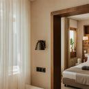 Metal wall sconce with wine glass silhouette casting soft ambient uplight in modern interior setting