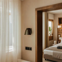 Metal wall sconce with wine glass silhouette casting soft ambient uplight in modern interior setting