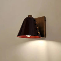 Metal wall sconce with wine glass silhouette casting soft ambient uplight in modern interior setting