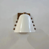 Metal wall sconce with wine glass silhouette casting soft ambient uplight in modern interior setting