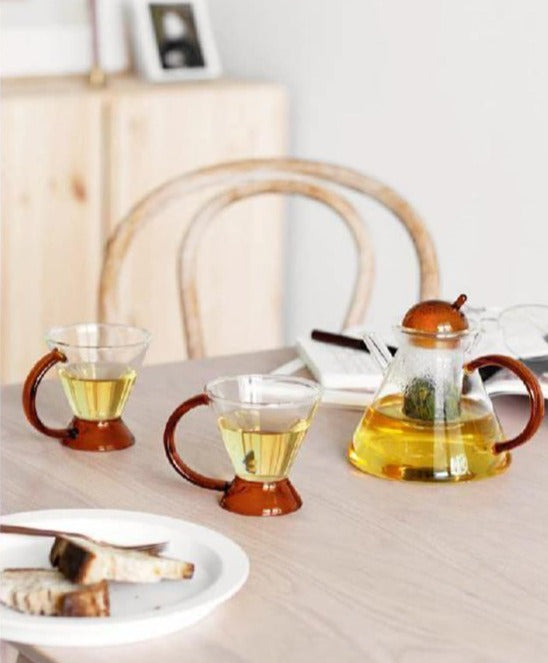 triangular clear borosilicate glass tea pot and cup with amber thin handle